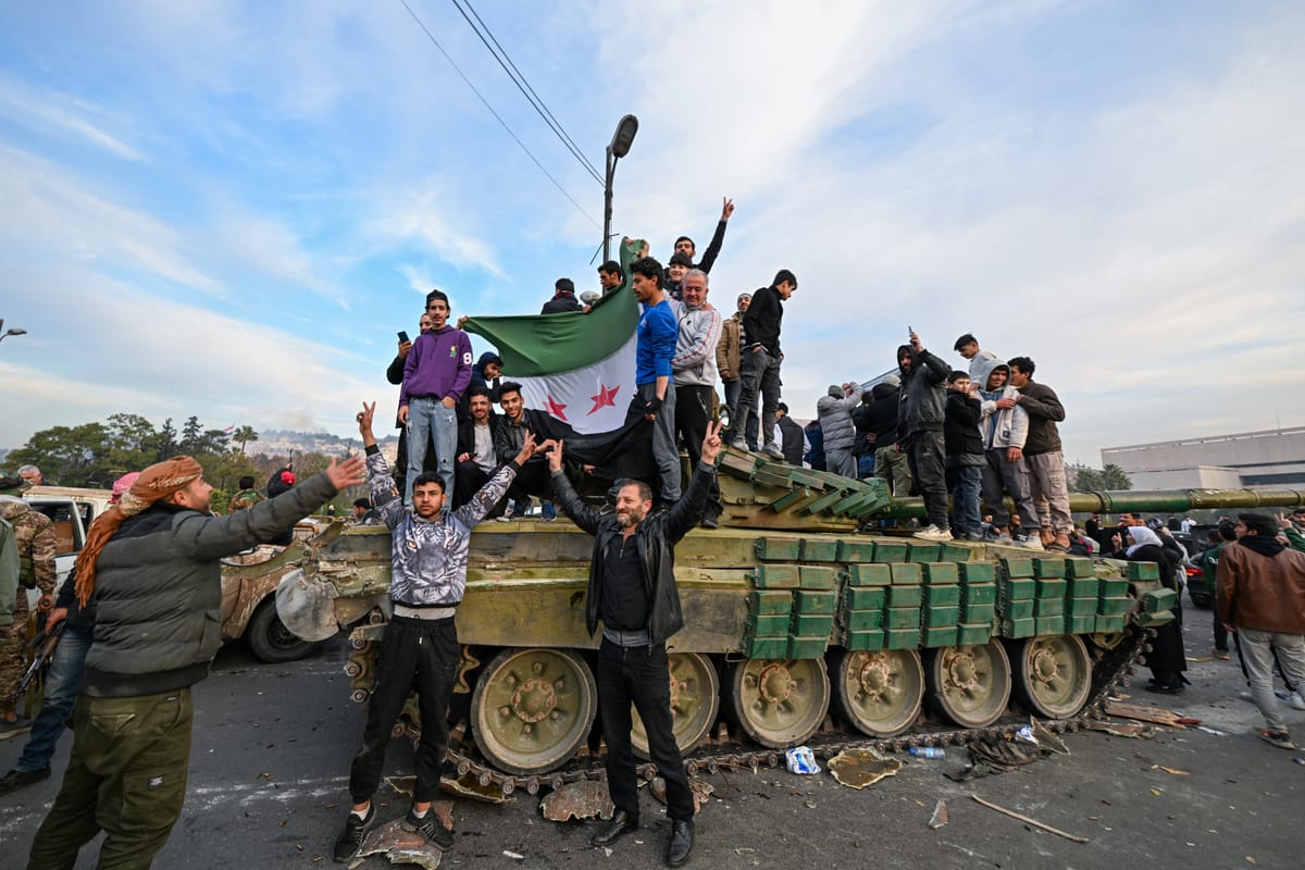 People celebrate with anti-government fighters in Damascus on December 8, 2024. (Photo by LOUAI BESHARA/AFP via Getty Images)