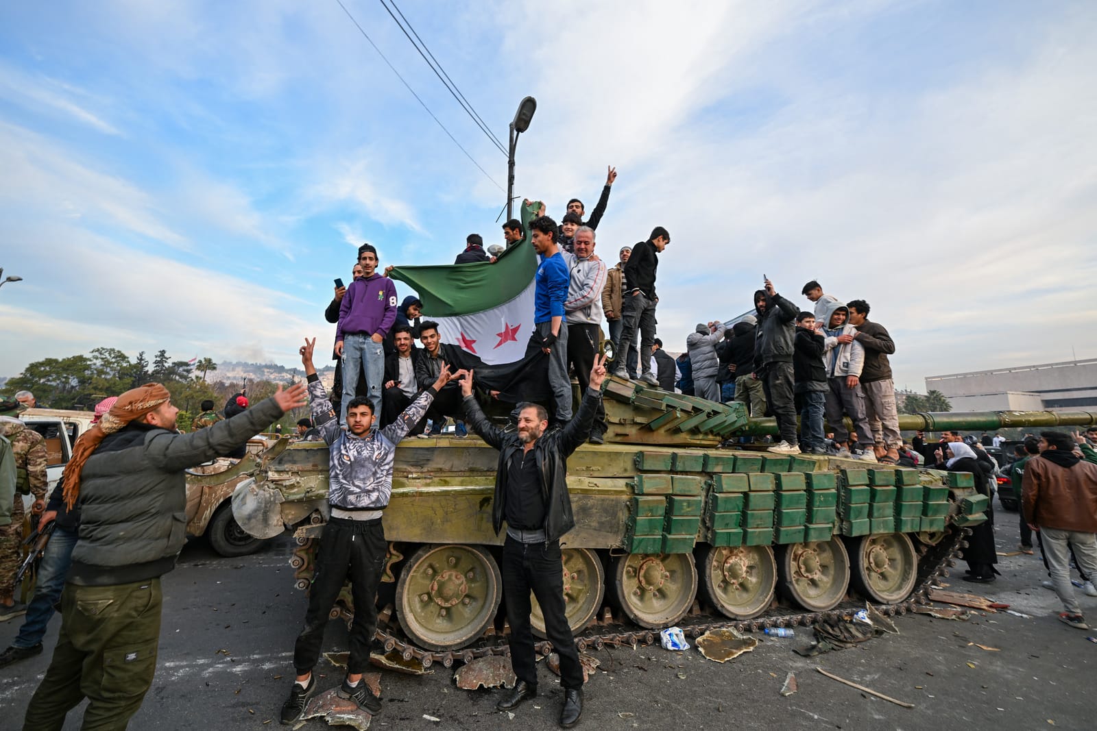 People celebrate with anti-government fighters in Damascus on December 8, 2024. (Photo by LOUAI BESHARA/AFP via Getty Images)