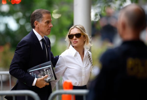 Hunter Biden, carrying his memoir, enters court with his wife. Photo by Kevin Dietsch/Getty Images